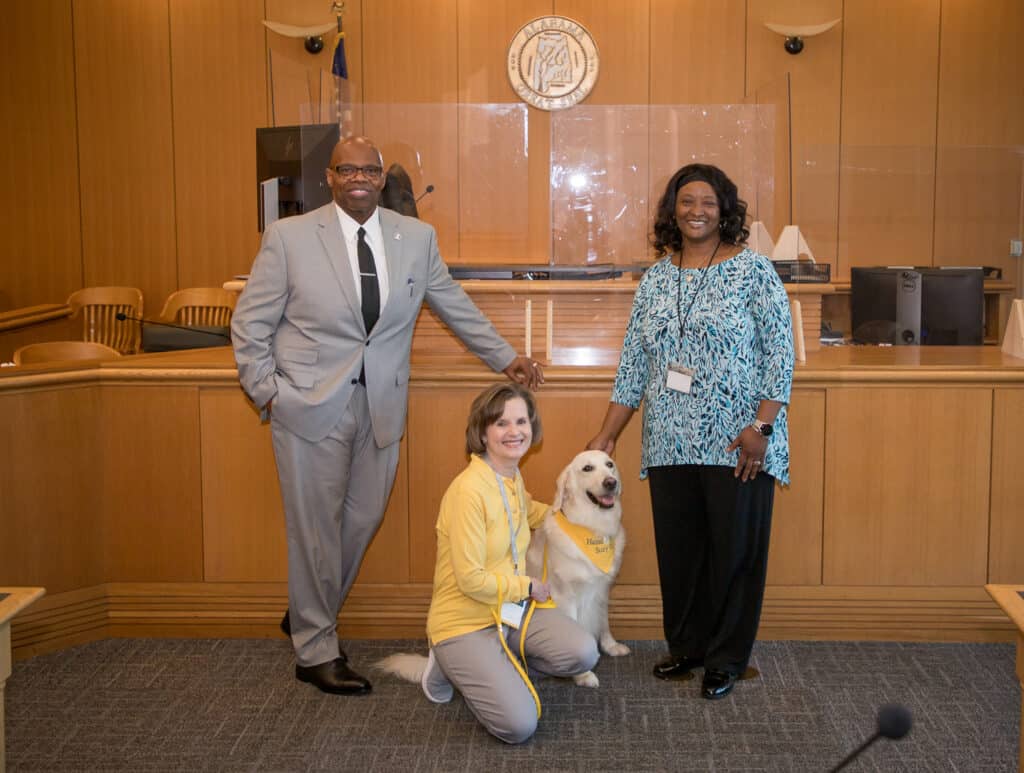 Hand in Paw volunteer Therapy Team with a therapy dog and civic leaders in a courthouse.
