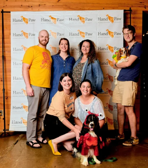 Brittany Filby and others pose in front of a Hand in Paw "step and repeat" banner at Barktoberfest in 2021.