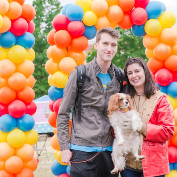 Brittany and Cooper Filby pose with their dog Chester in front of balloons at Mutt Strut 2019.