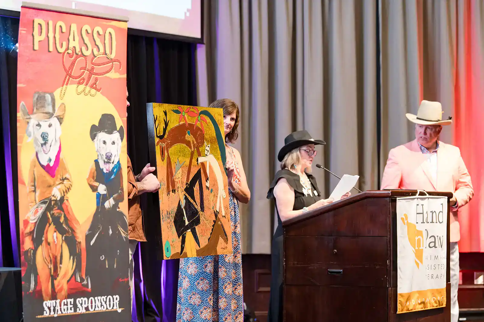 Amanda Summers holds up a Trés Taylor piece during the live auction at Picasso Pets 2024