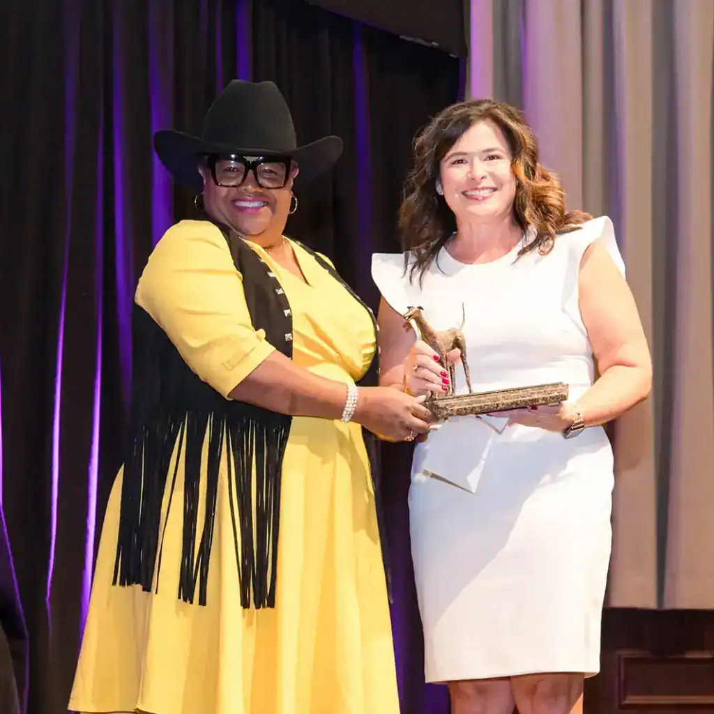 Two women accept an award at the Picasso Pets fundraiser supporting Hand in Paw's animal-assisted therapy mission.