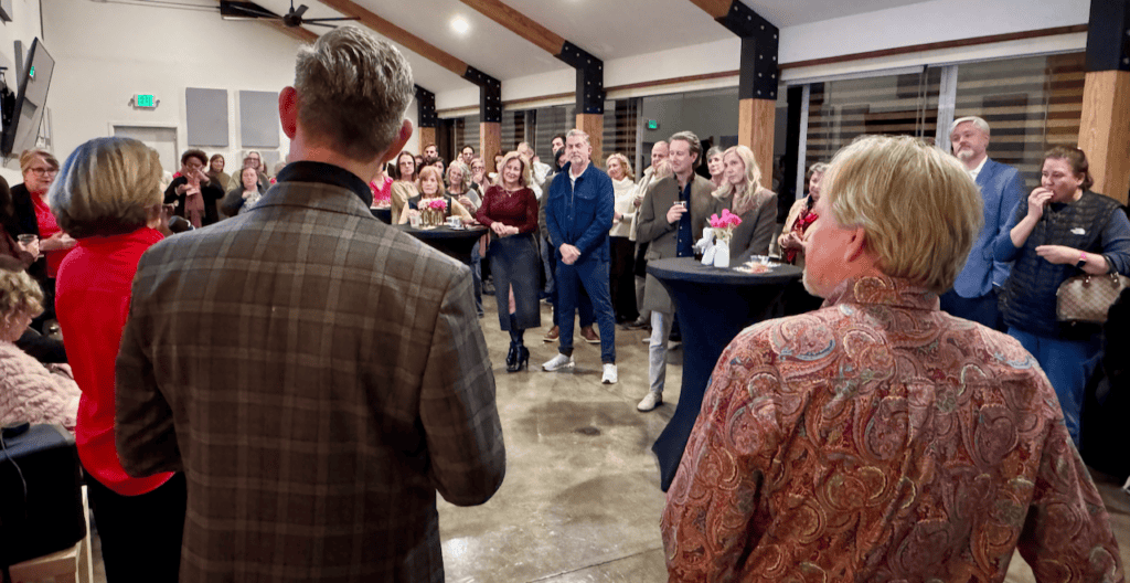 Community gathering with attendees listening to speakers at a Hand in Paw event