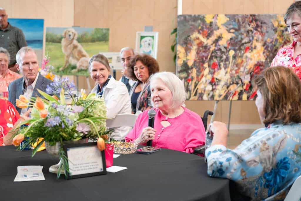Attendees gather around a floral centerpiece at Hand in Paw’s Gallery Party celebrating the organization’s founder.
