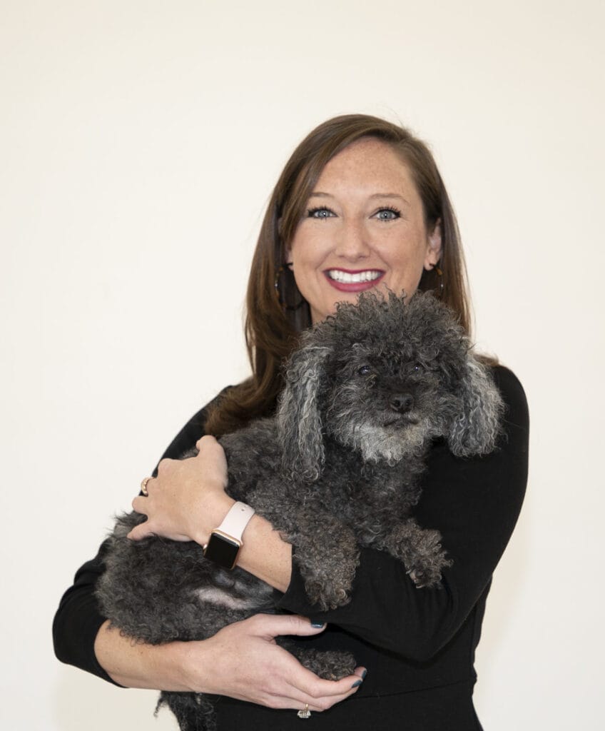 Volunteer holding a dog for Hand in Paw's animal-assisted therapy program.