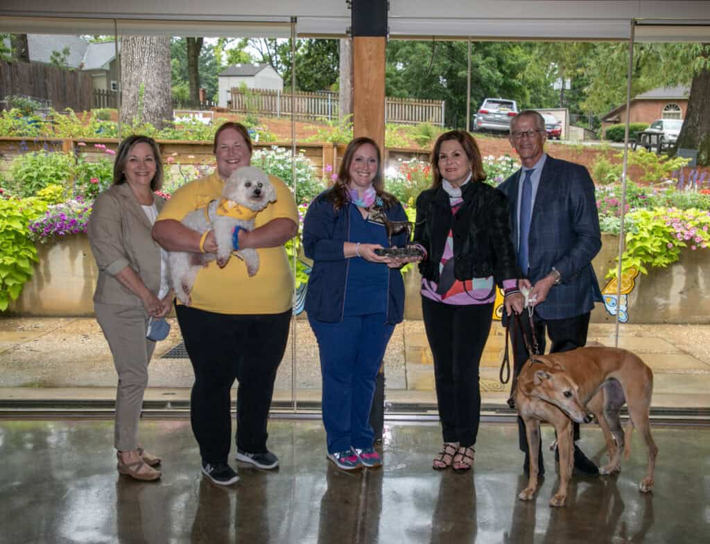 Hand in Paw volunteers and their therapy dogs pose together at an event.