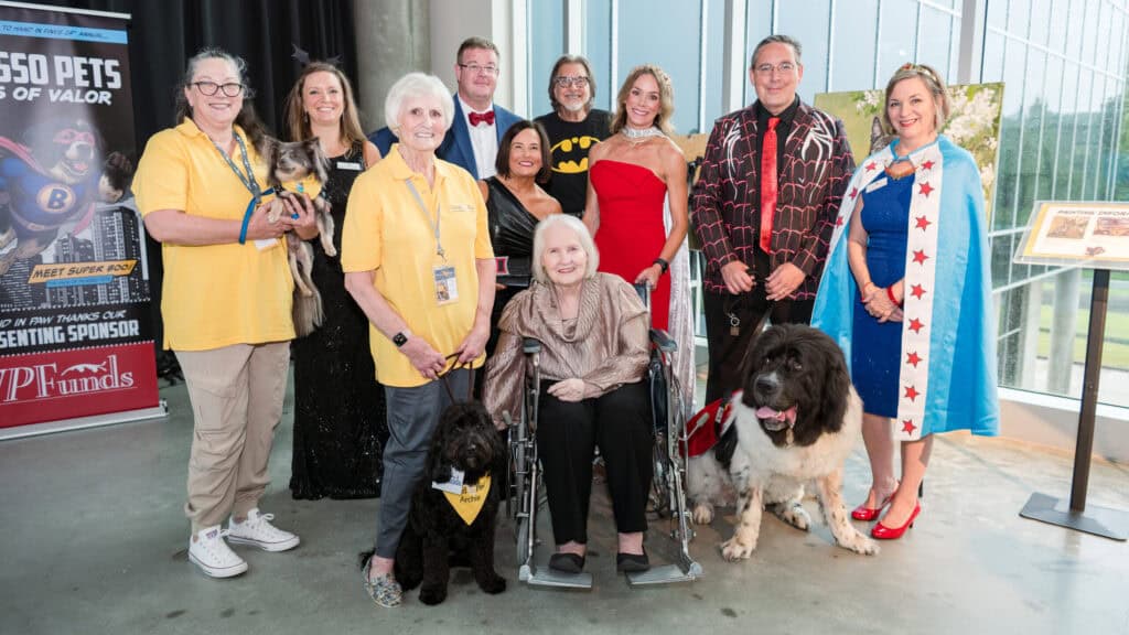 Hand in Paw volunteers and therapy dogs pose together at a community event.