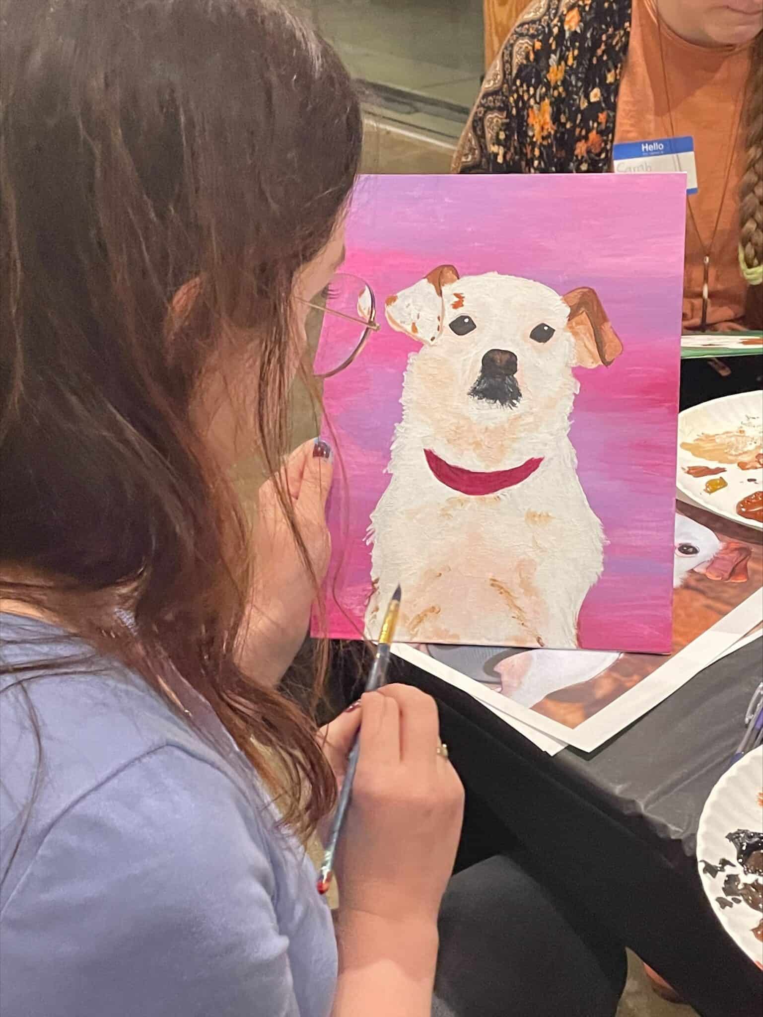 Child paints a portrait of a dog during a guided art activity.