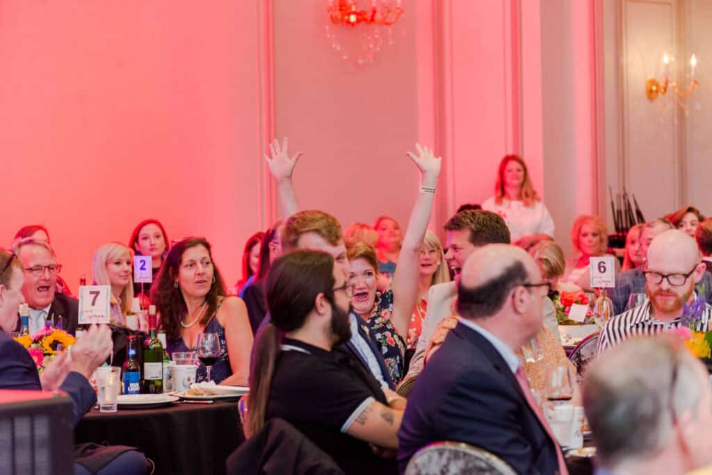 Attendees raise their hands during a Hand in Paw community event.